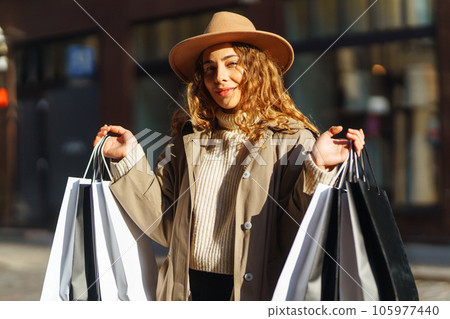 Happy woman with shopping bags walking on street. Purchases, black friday, discounts, sale concept. 105977440