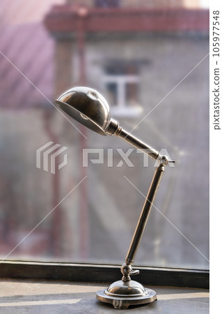 Minimal vintage style golden metallic lighting lamp on windowsill. Industrial building interior concept with copy space. Minimal vintage style golden metallic lighting lamp on windowsill. Industrial building interior concept with copy space. 105977548