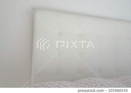 Soft headboard. Upholstery for furniture made of genuine or artificial leather and fabric. Soft headboard against a light wall Soft headboard. Upholstery for furniture made of genuine or artificial leather and fabric. Soft headboard against a light wall 105980545