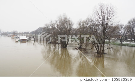 Macvanska Mitrovica, Serbia, 01/27/2023 The bridge over the Sava River. Flooding after heavy rains and snowmelt. A swift flow of muddy water. Trees, boats and piers in the water. Machva in winter Macvanska Mitrovica, Serbia, 01/27/2023 The bridge over the Sava River. Flooding after heavy rains and snowmelt. A swift flow of muddy water. Trees, boats and piers in the water. Machva in winter 105980599