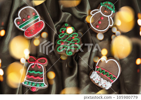Banner for Christmas and New Year gingerbread. Christmas trees, toys, snowmen, garlands on a background of brown silk fabric. Bright bokeh. 105980779