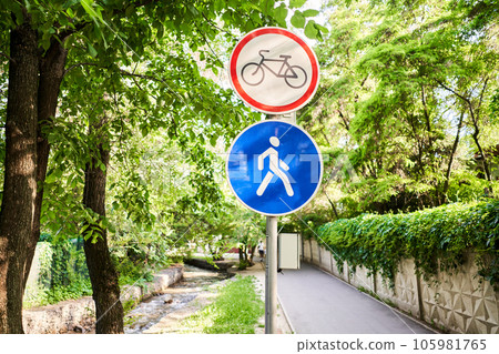 View of a generic no cycling sign on a pedestrian footpath. The no cycling sign denotes that the use of bicycles, e-bicycles, scooters, e-scooters and skateboards is banned View of a generic no cycling sign on a pedestrian footpath. The no cycling sign denotes that the use of bicycles, e-bicycles, scooters, e-scooters and skateboards is banned 105981765
