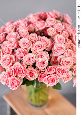 Glass vase with bush spray roses. The florist takes care of the flowers. A girl with a vase of flowers in her hands. Glass vase with bush spray roses. The florist takes care of the flowers. A girl with a vase of flowers in her hands. 105981810