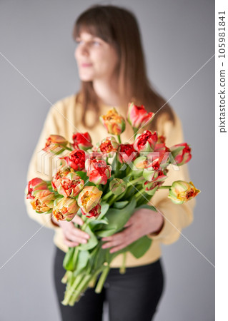 Tulip Gudoshnik in woman hand. Spring bouquet of red tulips in hands. Bunch of fresh cut spring flowers 105981841