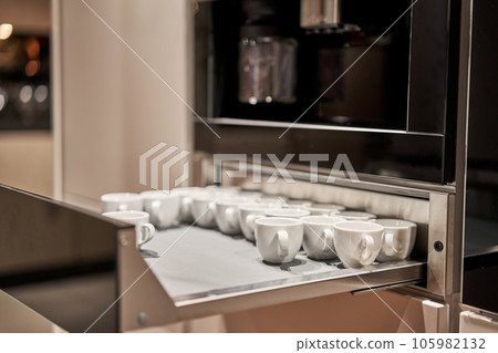 Cabinets for heating dishes. Glasses, dishes and bowls in a cabinet in a kitchen. Kitchen storage organization. Details of the interior of the kitchen in the house. Cabinets for heating dishes. Glasses, dishes and bowls in a cabinet in a kitchen. Kitchen storage organization. Details of the interior of the kitchen in the house. 105982132