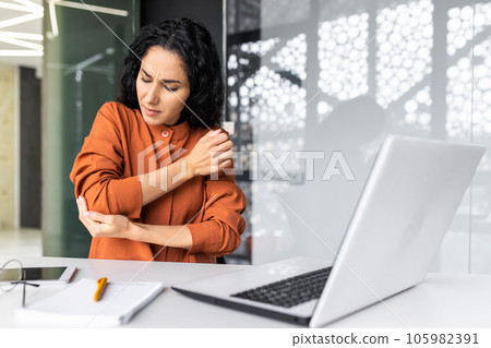 Businesswoman at the workplace sits tired and overworked, has severe pain in her hands and elbow joints. 105982391
