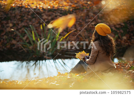 Seen from behind stylish woman in beige coat and hat sitting Seen from behind stylish woman in beige coat and hat sitting 105982575