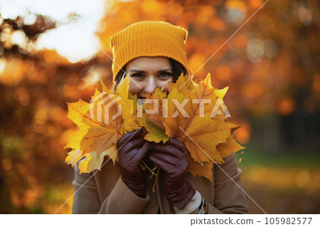 happy stylish woman in beige coat and orange hat 105982577