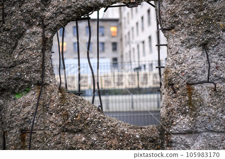 Hole in Broken Berlin wall and walking person against 105983170