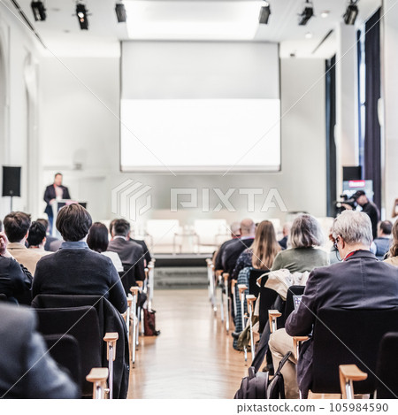 Speaker giving a talk in conference hall at business event. Rear view of unrecognizable people in audience at the conference hall. Business and entrepreneurship concept Speaker giving a talk in conference hall at business event. Rear view of unrecognizable people in audience at the conference hall. Business and entrepreneurship concept 105984590