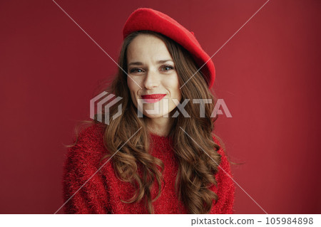 happy woman in red sweater and beret against red background 105984898