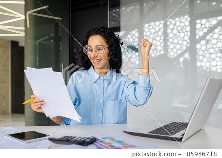 Happy and successful woman financier on paper work, satisfied with the results of the achievement, happy businesswoman holding papers, contracts and bills reports, hispanic woman inside the office. Happy and successful woman financier on paper work, satisfied with the results of the achievement, happy businesswoman holding papers, contracts and bills reports, hispanic woman inside the office. 105986718