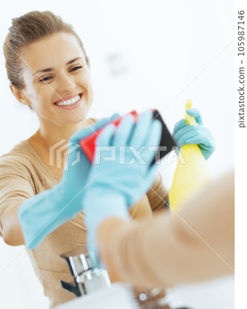 Happy young housewife cleaning mirror in bathroom 105987146