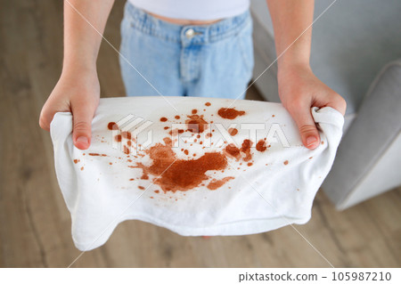 The child spilled coffee on his clothes. The concept of a stain on a t-shirt. Top view. 105987210