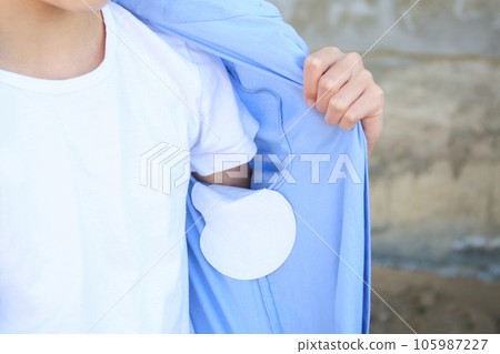 The teenager shows a strip of sweat attached to the armpits of shirt. The teenager shows a strip of sweat attached to the armpits of shirt. 105987227