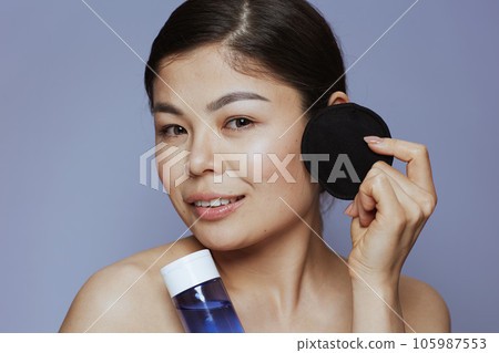 modern asian woman with makeup remover and black cotton pad 105987553