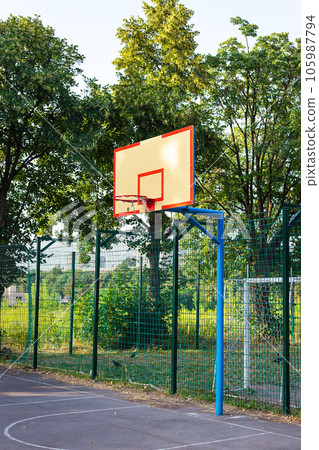 Empty basketball court on a sunny day. Basketball ring and court on the background of nature. 105987794