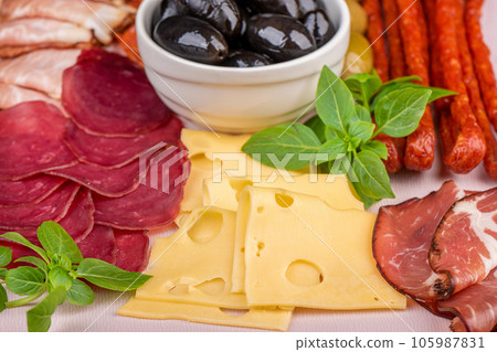 Close-up of slicing cheese, sausages, prosciutto with olives. 105987831
