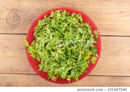 Top view of chopped parsley leaves in a plate over wooden background. 105987846