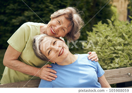 Happy middle age women hug and look at camera on city park. Female friendship 105988059