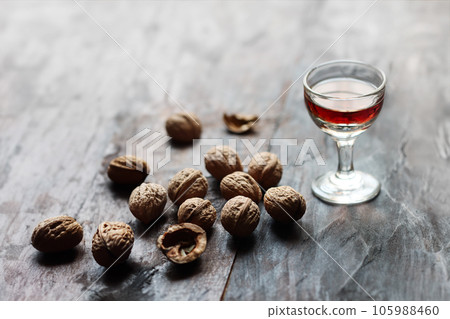 A glass of walnut liquor and walnuts on the old wooden table in backlight 105988460