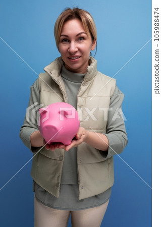 young blond hair woman is going to invest the accumulated money from the piggy bank into a purchase 105988474