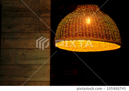 Glowing electric lamp in a wicker lampshade at dusk.Place for text 105988745