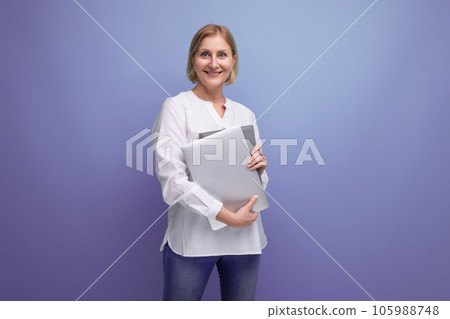 middle-aged woman with blond hair solves work tasks using a laptop 105988748