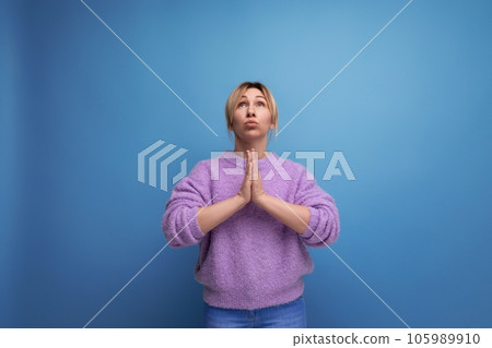attractive blond young millennial woman in casual look praying with folded hands together on bright attractive blond young millennial woman in casual look praying with folded hands together on bright 105989910