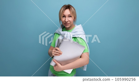 blond attractive business lady in a casual look with a laptop in her hands on a blue background blond attractive business lady in a casual look with a laptop in her hands on a blue background 105990256