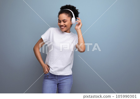 young brunette latin woman in a white t-shirt listens to her favorite music in bluetooth headphones 105990301