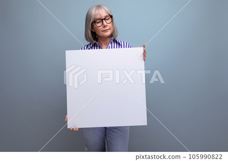 gray-haired mature woman showing blank sheet with mockup on bright studio background gray-haired mature woman showing blank sheet with mockup on bright studio background 105990822