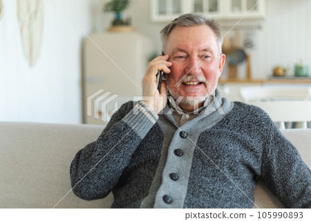 Happy middle aged senior man talking on smartphone with family friends. Older mature grandfather with cell phone talking with grown up children, resting at home. Older generation modern tech usage Happy middle aged senior man talking on smartphone with family friends. Older mature grandfather with cell phone talking with grown up children, resting at home. Older generation modern tech usage 105990893