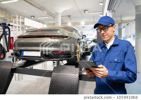 Serviceman with digital tablet on the background of the car in the car service. Serviceman with digital tablet on the background of the car in the car service. 105991068
