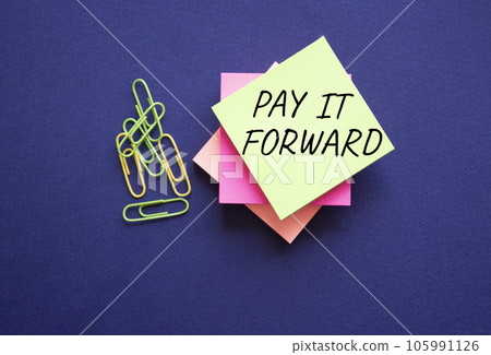 Pay it forward symbol. Concept words Pay it forward on yellow steaky note with paper clips. Beautiful pink background. Business and Pay it forward concept. Copy space. 105991126