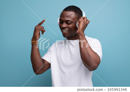 well-groomed adorable 30s african man with short haircut in white t-shirt enjoying music on 105991346