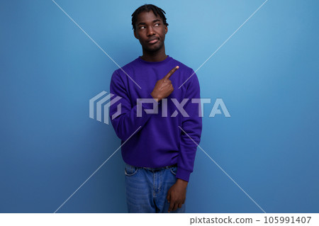 portrait of a doubtful dark-skinned european young adult in a blue hoodie and jeans isolated on a 105991407