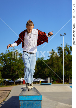 Teenager rollerskater balancing on pedestal performing extremely ride tricks Teenager rollerskater balancing on pedestal performing extremely ride tricks 105992171