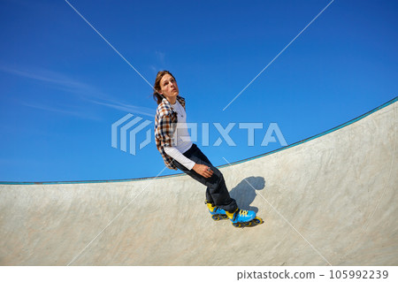 Teenager guy wearing roller skates performing extreme wall-ride element Teenager guy wearing roller skates performing extreme wall-ride element 105992239