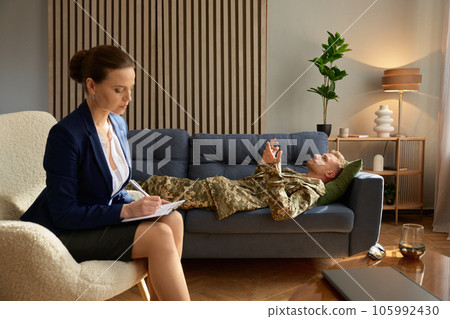 Man soldier with PTSD lying on sofa talking to psychotherapist 105992430