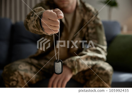 Closeup military hand holding metallic badge dog tag with qr code 105992435