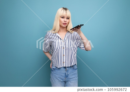 cute blond young lady in casual outfit with smartphone in studio cute blond young lady in casual outfit with smartphone in studio 105992672