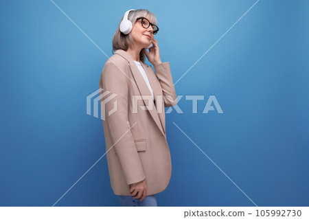 successful mature business lady with wireless headphones enjoying music on bright background with 105992730