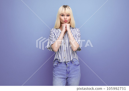 charming blond caucasian smiling 20s woman in striped shirt on studio background with copy space 105992731