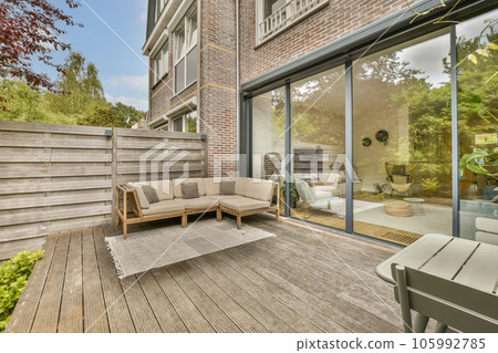 an outside living area with wood flooring and sliding glass doors leading to the decked back yard on a sunny day 105992785