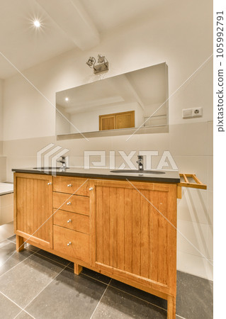 a bathroom with two sinks and a large mirror on the wall in the photo is taken to the right side 105992791