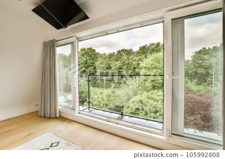 a bedroom with a large window looking out at the trees outside and an area rug on the floor to the right 105992808
