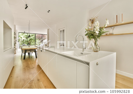 a kitchen and dining area in a house with wood flooring, white cabinets and an open door leading to the patio a kitchen and dining area in a house with wood flooring, white cabinets and an open door leading to the patio 105992828