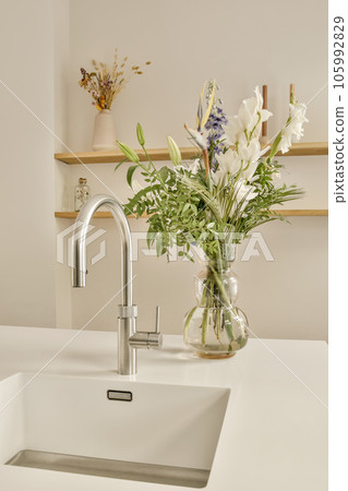 some flowers in a vase on the kitchen sink with wooden shelves and shelvings behind it to be used for storage some flowers in a vase on the kitchen sink with wooden shelves and shelvings behind it to be used for storage 105992829