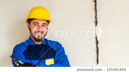 Portrait of worker or engineer in blue work clothes and yellow safety helmet 105992898